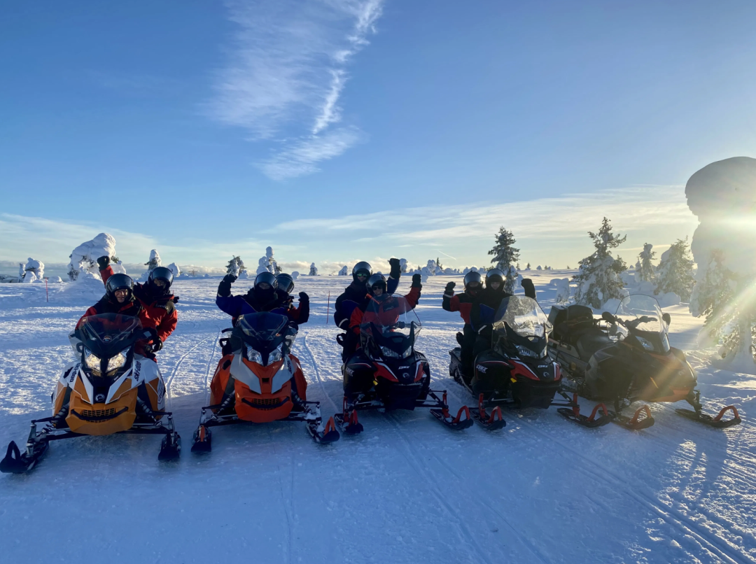 Snowmobiles and their happy drivers in a sunny winter weather in Finnish Lapland