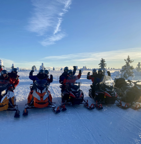 Snowmobiles and their happy drivers in a sunny winter weather in Finnish Lapland