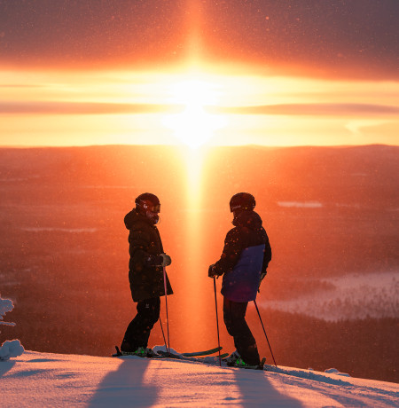 Two skiers at Pyhä Ski Resort Lapland in sunset
