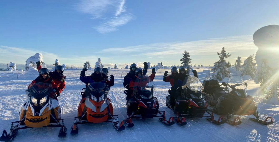 Snowmobiles and their happy drivers in a sunny winter weather in Finnish Lapland