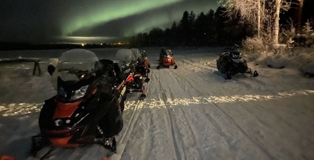 A snowmobile on a frozen lake Pyhäjärvi under the green northern lights